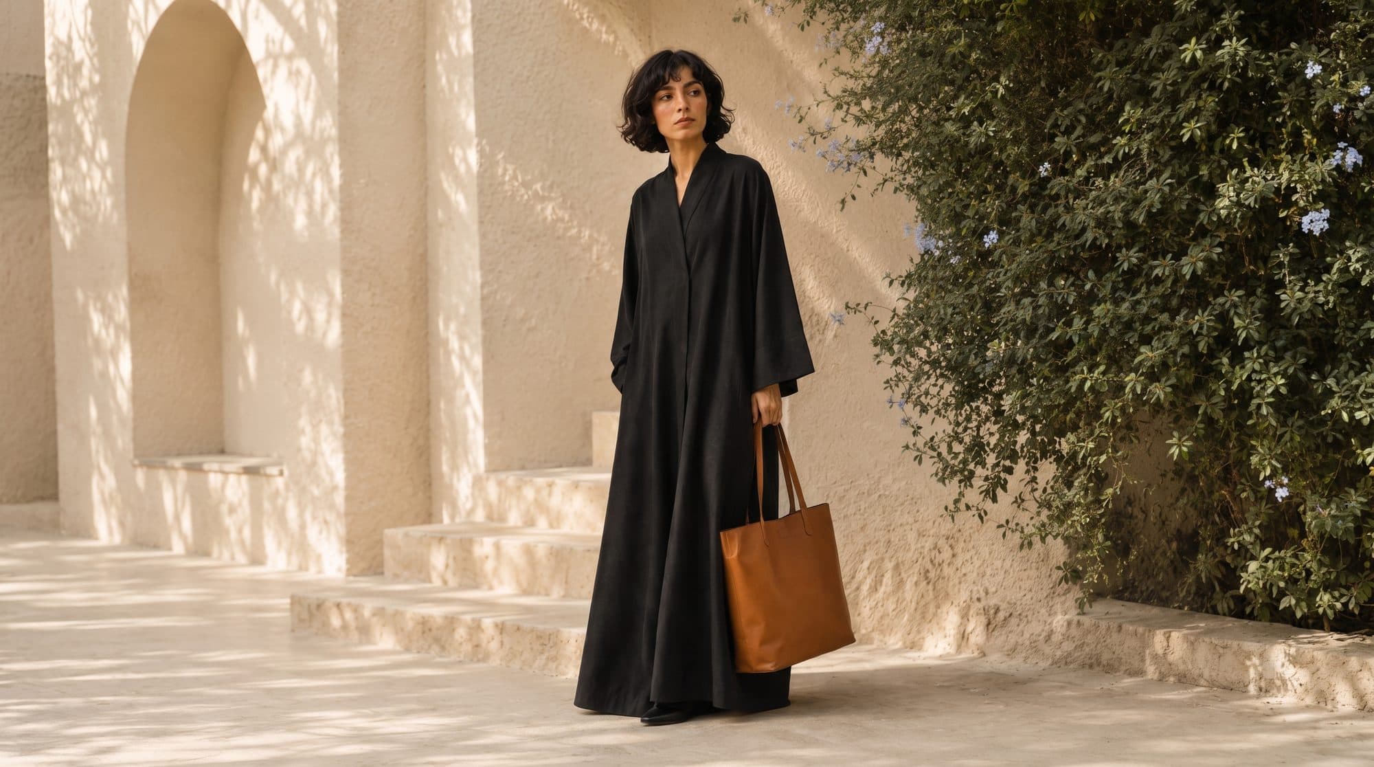 A black abaya carried through a sunlit courtyard